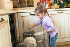 Child putting dishes in dish washer