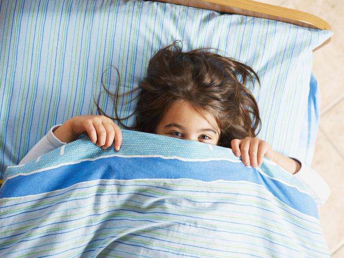 Child in bed with covers up to her nose
