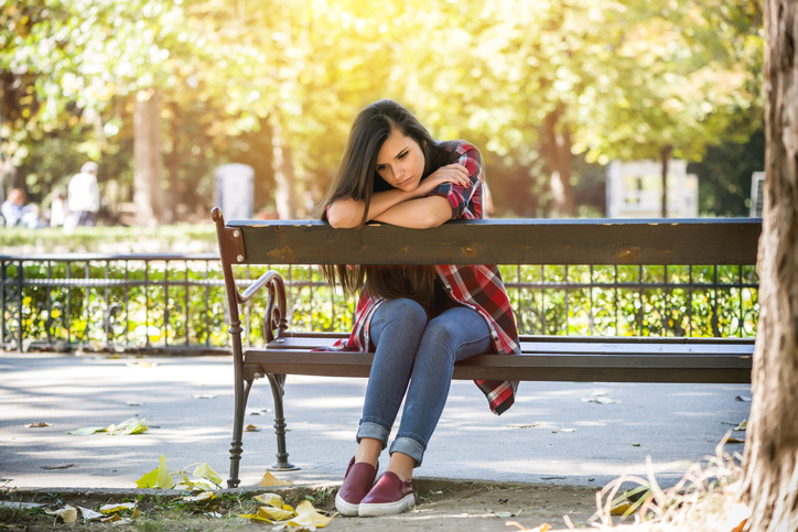 Upset teen girl sitting on a bench
