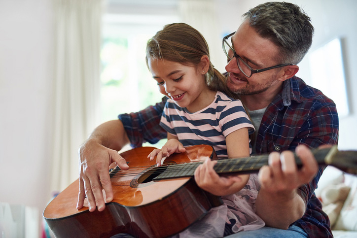 Dad teaching daughter to play guitar