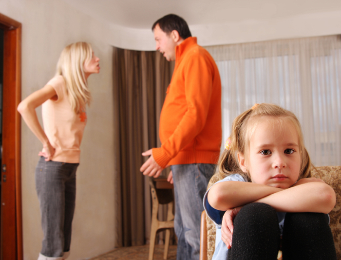 Upset child with parents arguing in the background