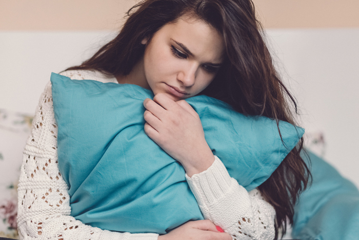 Upset teen clutching a pillow