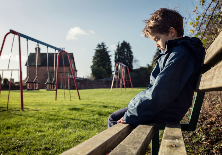 Sad child sitting on a bench