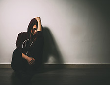 Teen sitting against a wall, upset