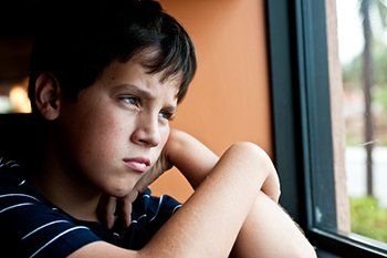 sad boy looking out a window