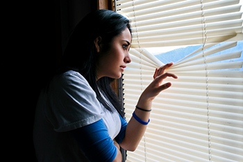 Person looking through blinds on a window