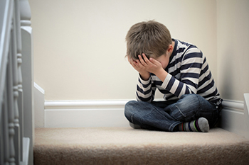 Child sitting on stairs, head in hands