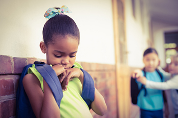 Sad girl standing by group of bullies