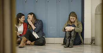 Teen sitting against lockers, alone