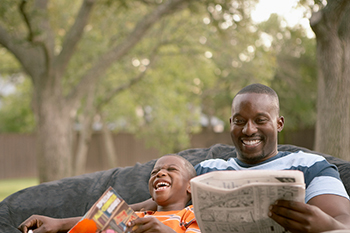 Father and son reading outside