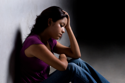 Upset teen sitting against a wall