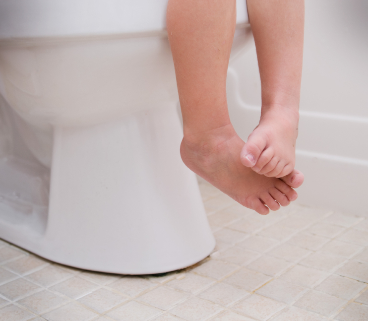 Child's feet dangling over toilet