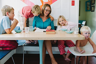 Mom sittign at a table with four children.