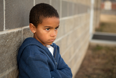 Angry child leaning against a wall