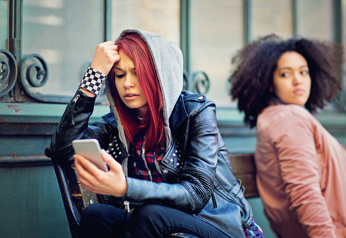 teen sitting on a bench looking at her phone