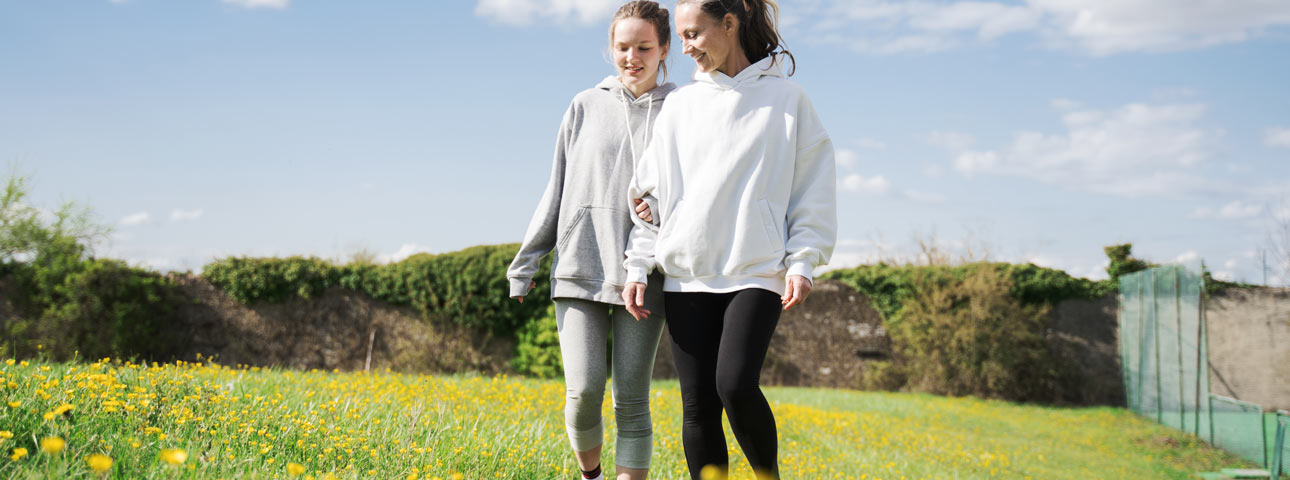 Mom and daughter walk happily in field of dandelions